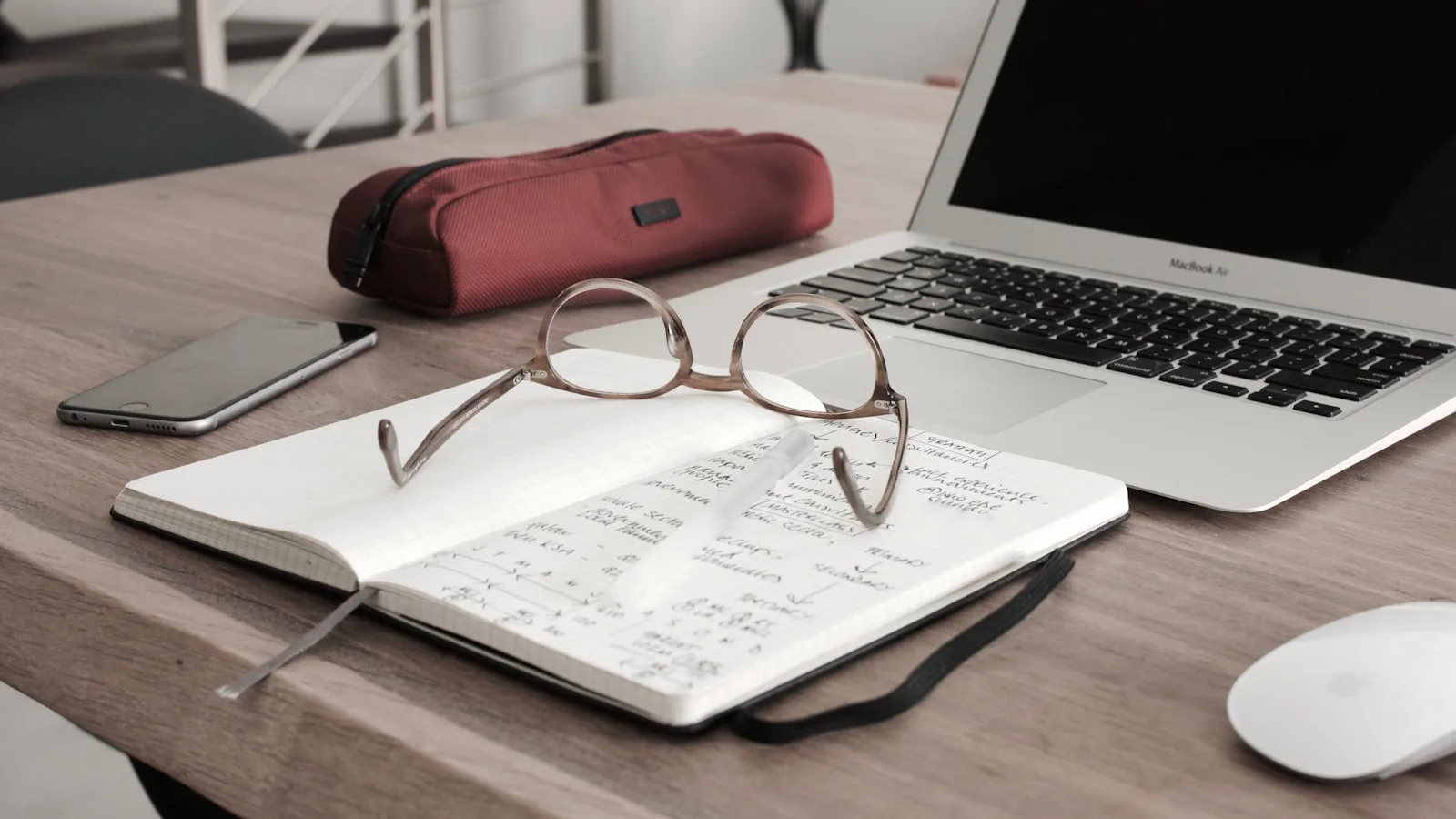 Photo of a work desk with glasses and a diary.