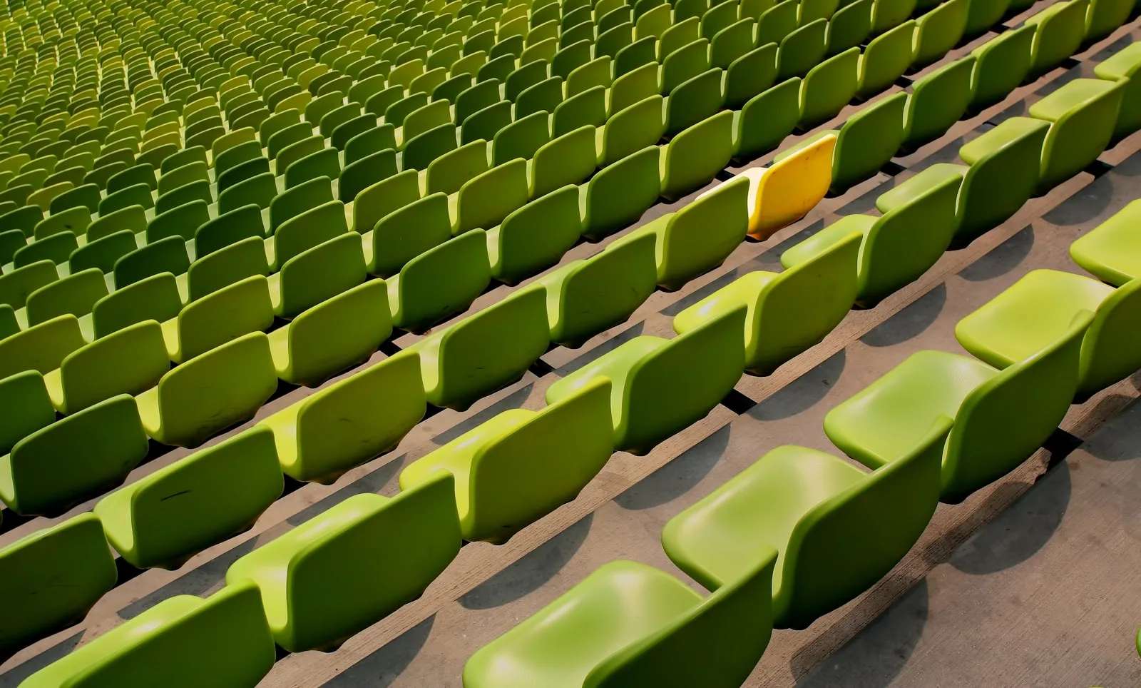 Image of one yellow chair standing out form all the green chairs