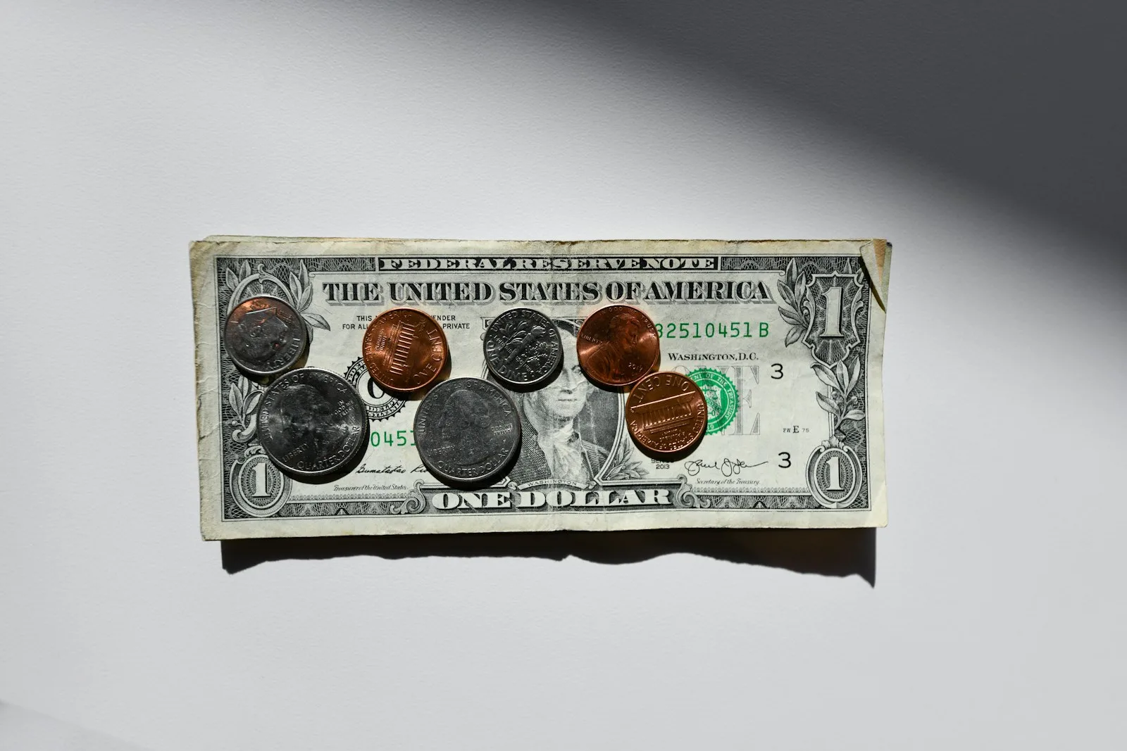 Photo of a one dollar bill with an exact change on top of it.