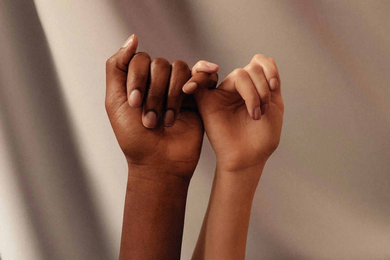 Two people crossing fingers as a sign of making a promise.