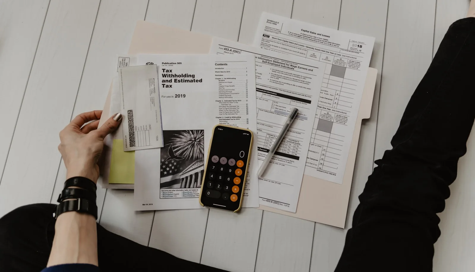 A person doing personal budgeting and tax calculation by looking at their financial documents and reports