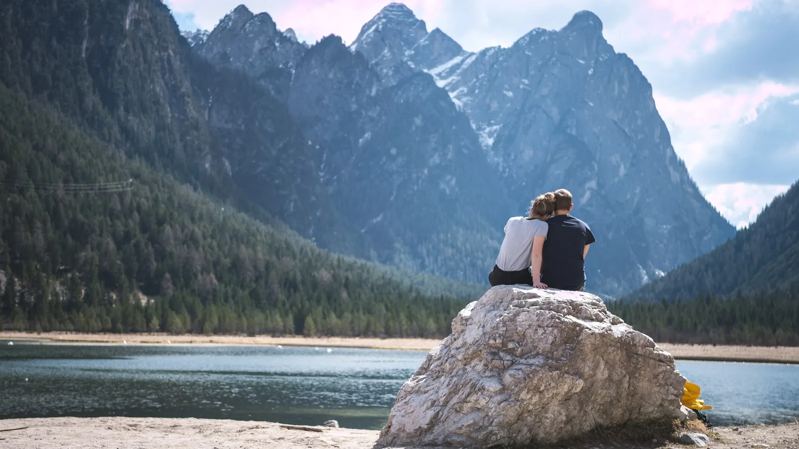 An image of a couple enjoying the view of mountains and lake