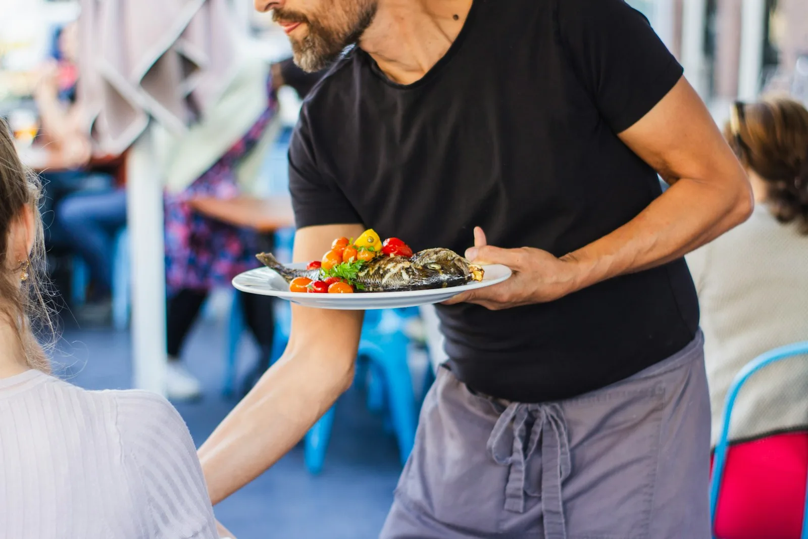 A person working as a waiter on the side in order to increase his passive income streams