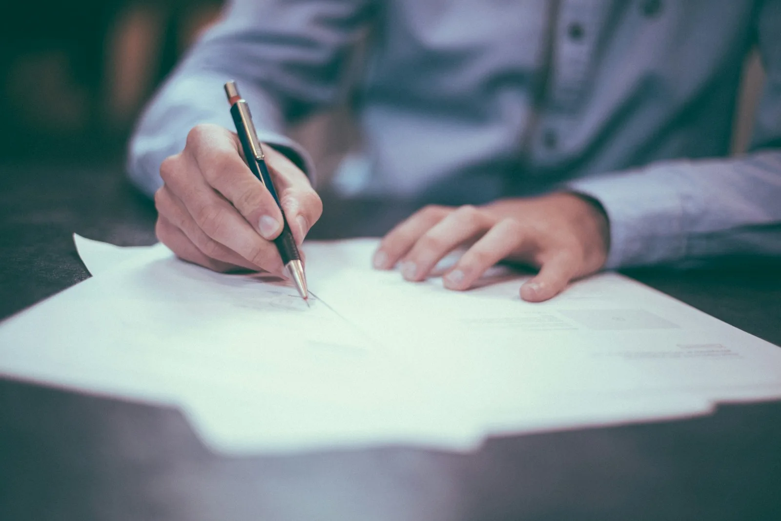 A person performing paperwork with a pen