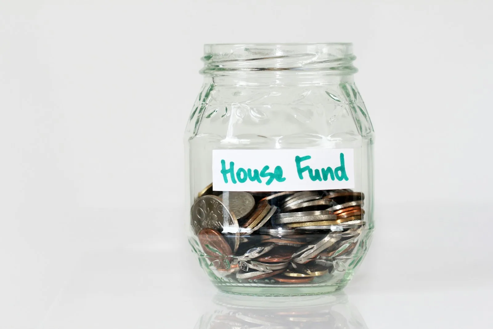 A jar of coin with the label “House Fund”. A way of saving your money for major life events.