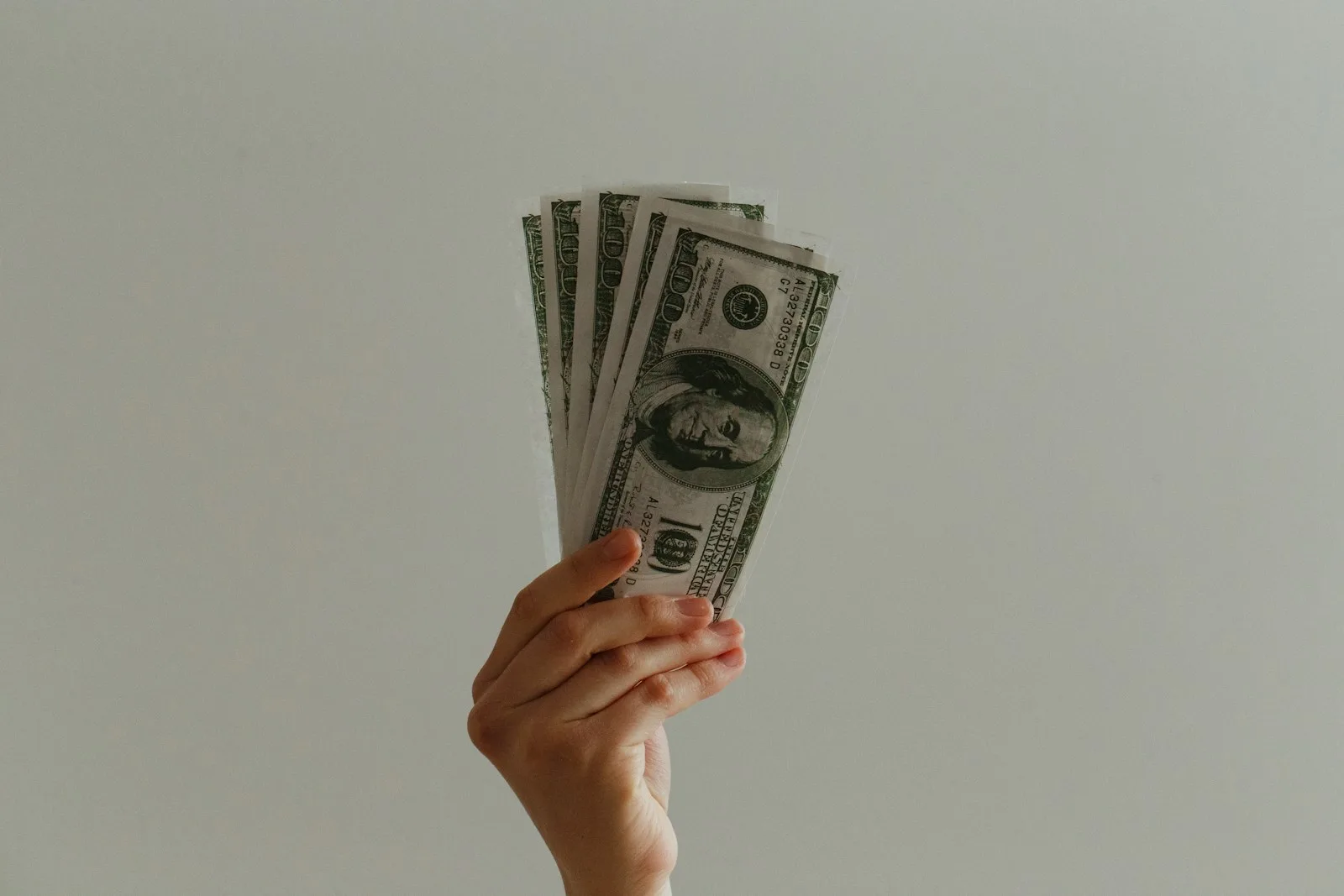 Image of a person holding out a bunch of US Dollars notes